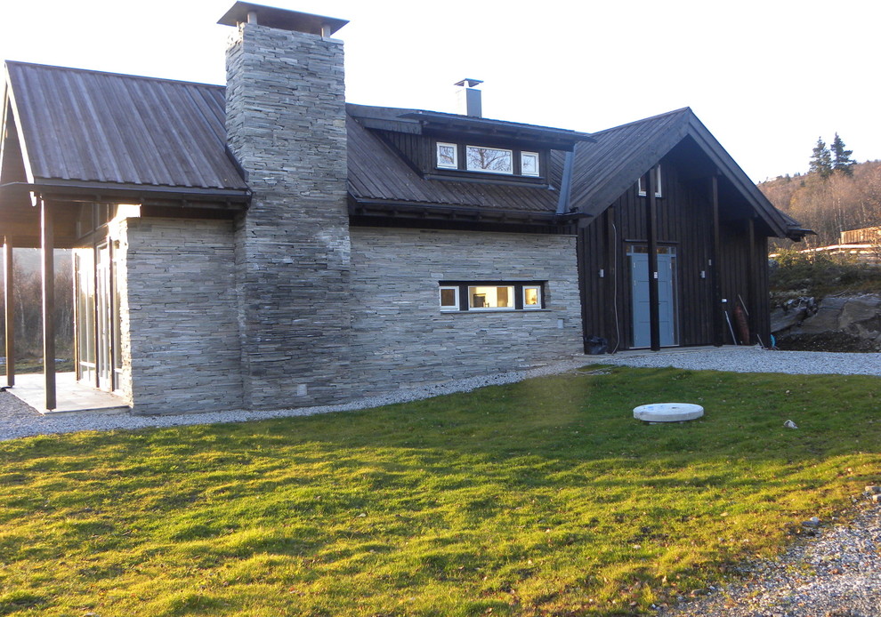 This is an example of a medium sized and black contemporary two floor house exterior in Other with stone cladding and a pitched roof.