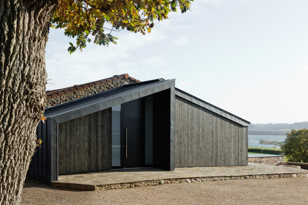 Cette photo montre une façade de maison tendance en bois avec un toit à deux pans et un toit en métal.