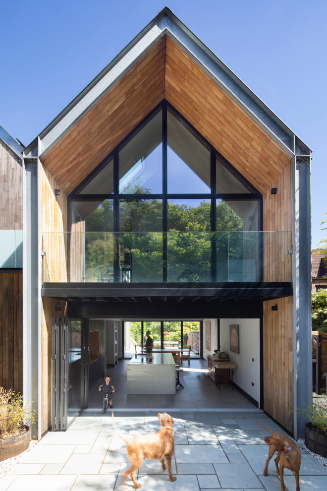 Cette photo montre une grande façade de maison tendance en bois avec un toit à deux pans et un toit en métal.