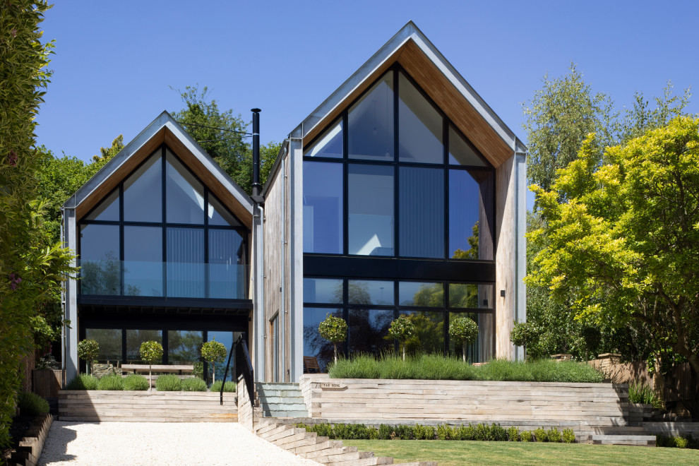 Modelo de fachada de casa contemporánea grande de dos plantas con revestimiento de madera, tejado a dos aguas y tejado de metal