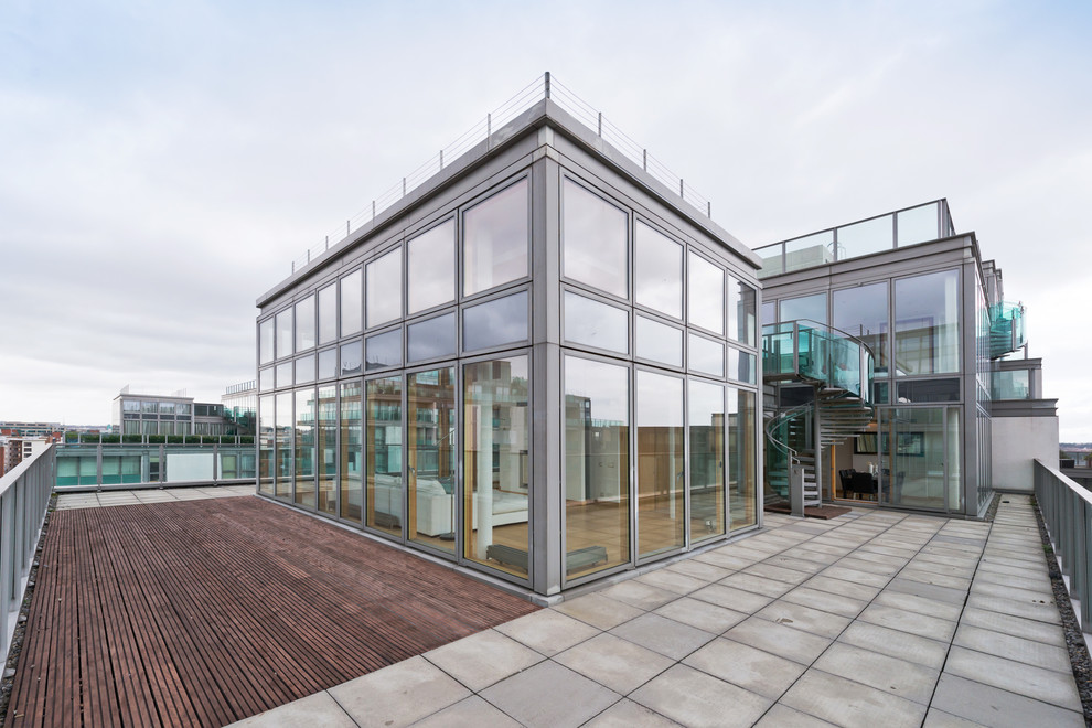 На фото: двухэтажный, стеклянный многоквартирный дом в современном стиле с плоской крышей с