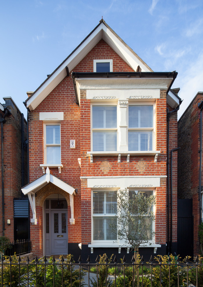 Inspiration for a red classic brick house exterior in London with three floors and a pitched roof.
