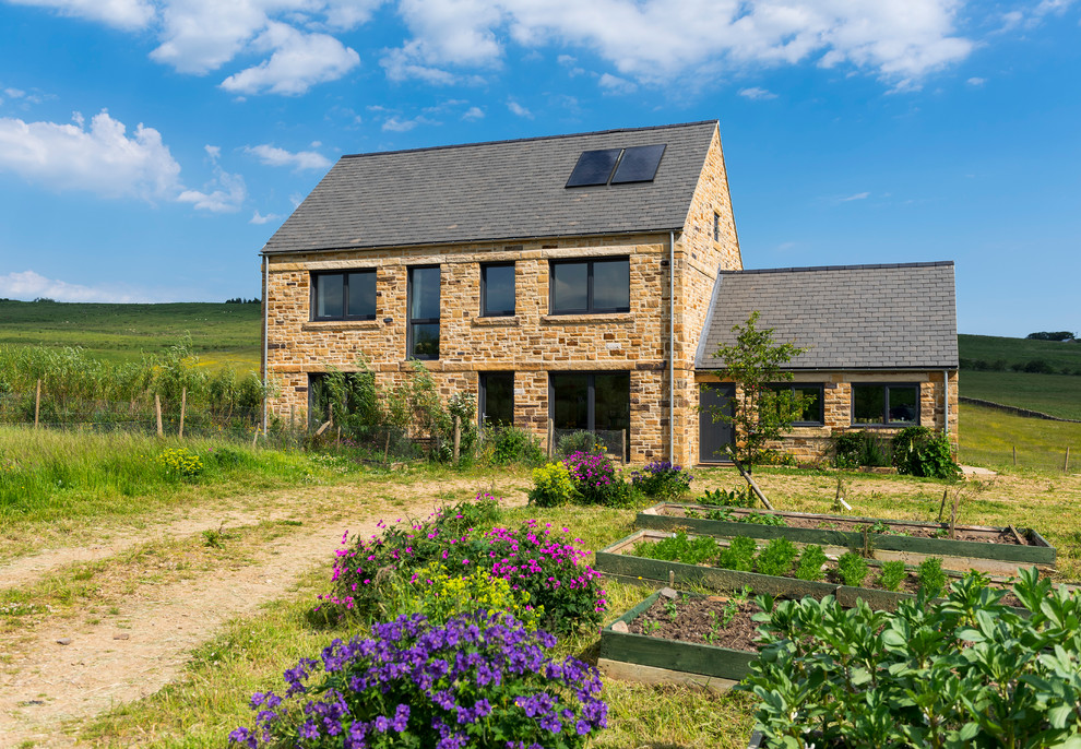 Photo of a rural two floor house exterior in Other with stone cladding and a pitched roof.
