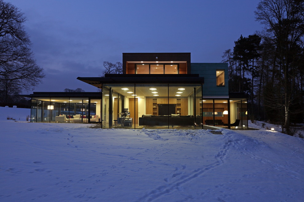 Imagen de fachada minimalista de dos plantas con revestimiento de vidrio y tejado plano
