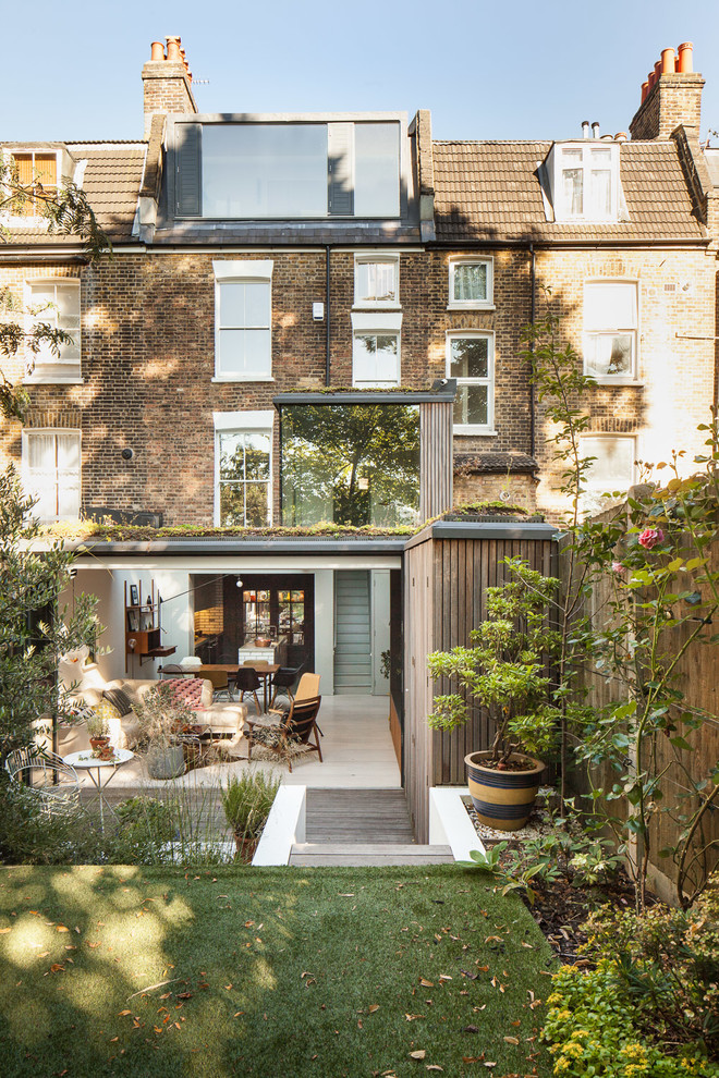 Medium sized and beige contemporary brick and rear house exterior in London with three floors.