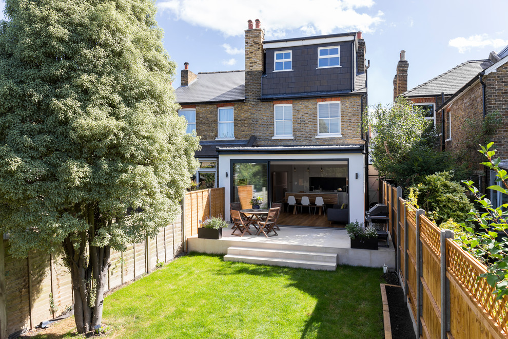 Medium sized and brown contemporary brick semi-detached house in London with three floors, a mansard roof and a shingle roof.