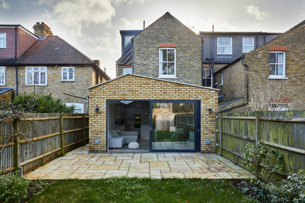 Inspiration for a beige modern house exterior in London with three floors, a half-hip roof and a tiled roof.