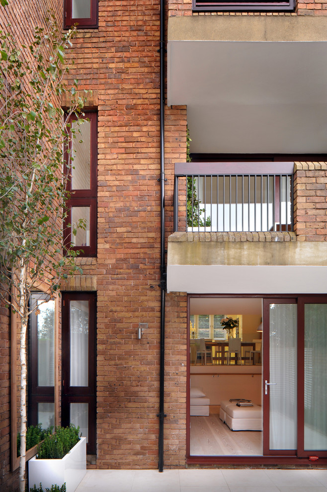 Example of a trendy three-story brick exterior home design in London