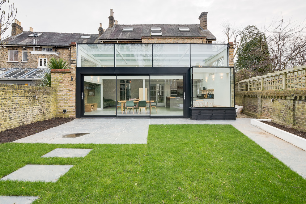 Inspiration for a large and black contemporary detached house in London with three floors, wood cladding, a flat roof and a mixed material roof.