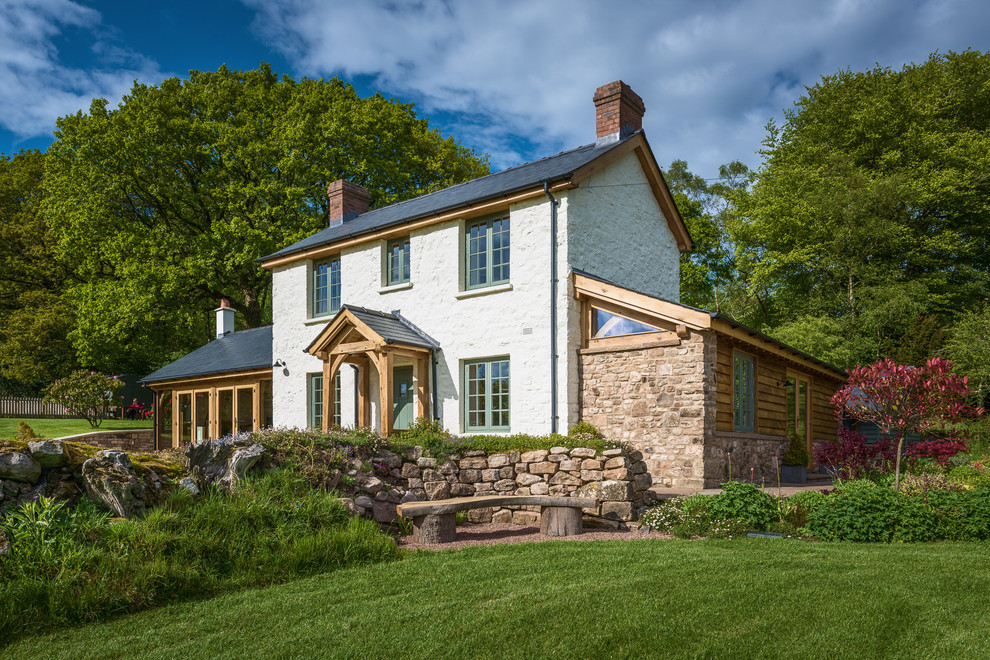 Zweistöckiges Landhausstil Einfamilienhaus mit Steinfassade, weißer Fassadenfarbe, Satteldach und Schindeldach in Sonstige