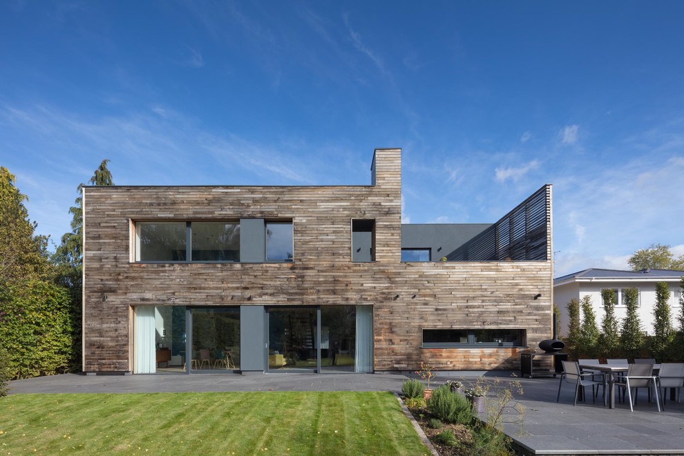 Идея дизайна: двухэтажный, деревянный, серый частный загородный дом среднего размера в современном стиле с плоской крышей и зеленой крышей
