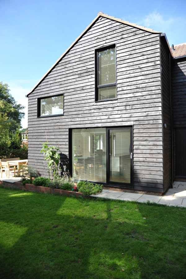 Photo of a medium sized and black contemporary two floor house exterior in Surrey with wood cladding.