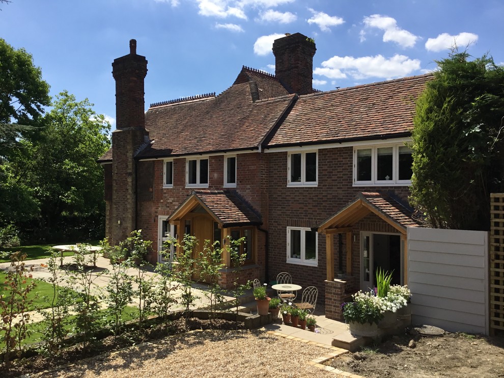 Mittelgroßes, Zweistöckiges Landhausstil Einfamilienhaus mit Backsteinfassade, brauner Fassadenfarbe, Walmdach und Ziegeldach in Sussex