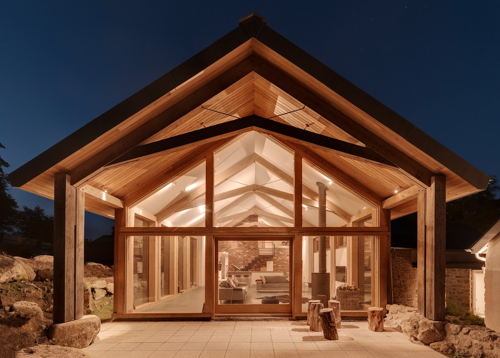 Réalisation d'une façade de grange rénovée design avec un revêtement mixte et un toit à deux pans.