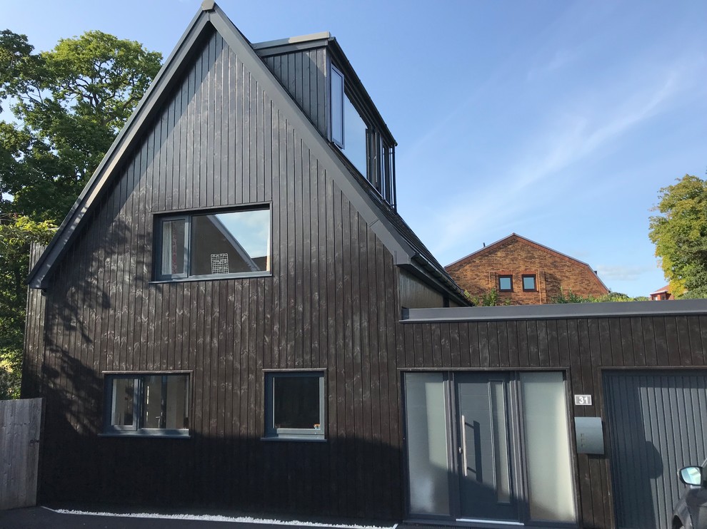 Immagine della villa nera scandinava a tre piani di medie dimensioni con rivestimento in legno, tetto a capanna e copertura in tegole