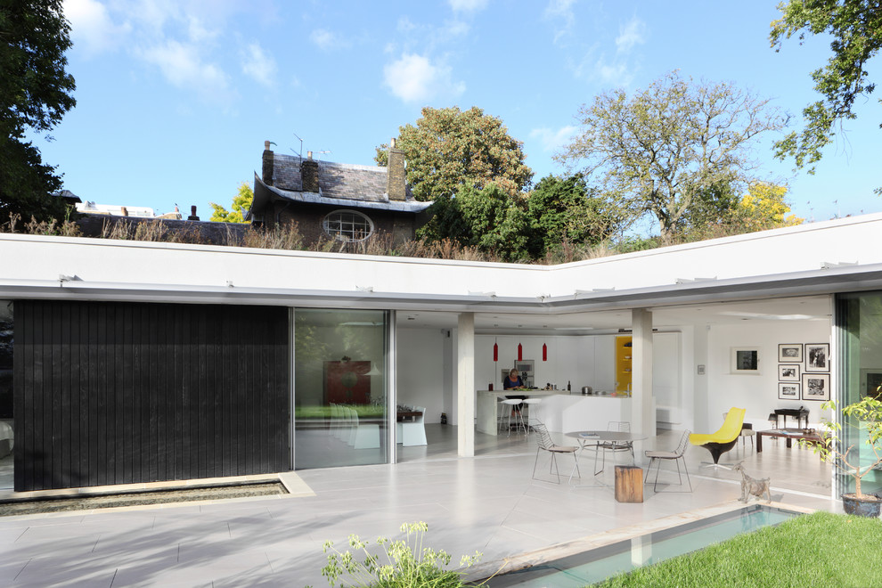 This is an example of a medium sized and white contemporary two floor house exterior in London with wood cladding.
