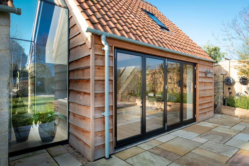 Ejemplo de fachada minimalista con revestimiento de madera, tejado a dos aguas y tejado de teja de barro