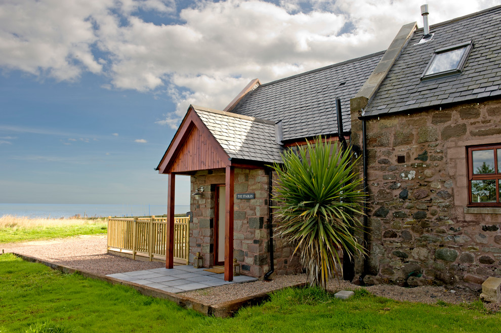 Foto della facciata di una casa stile marinaro con rivestimento in pietra e tetto a capanna