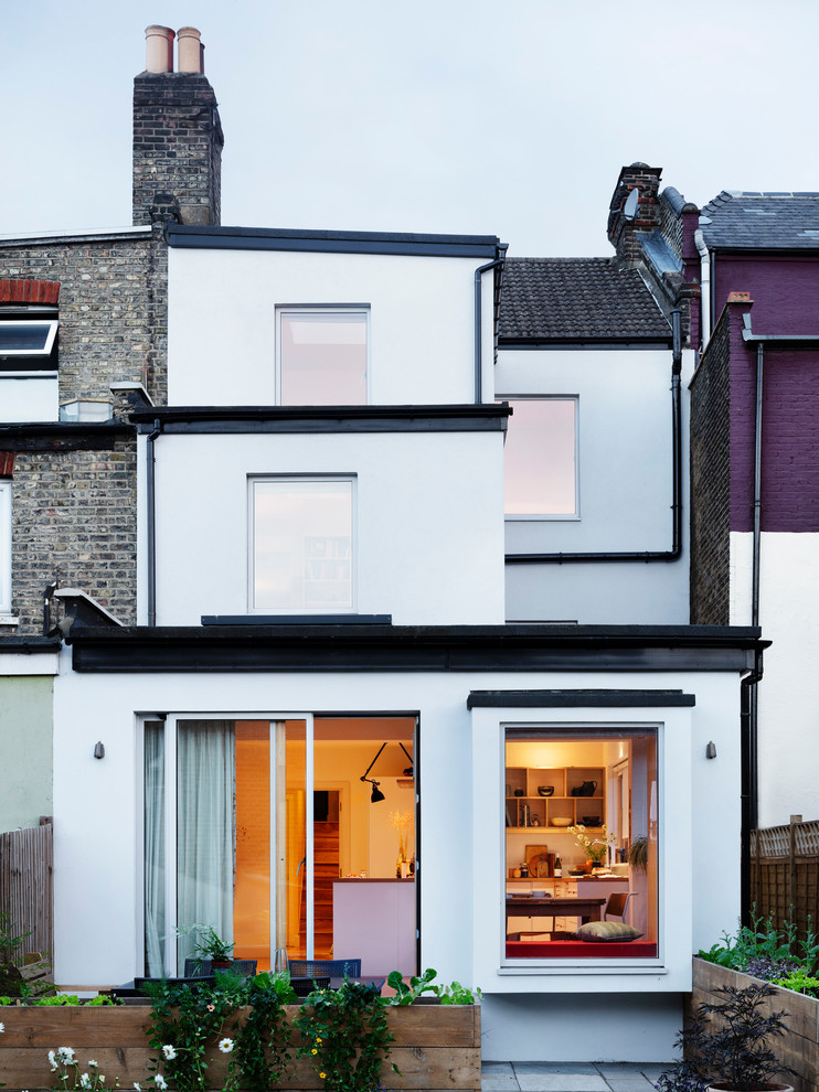 This is an example of a large and white scandi render terraced house in London with three floors, a flat roof and a mixed material roof.