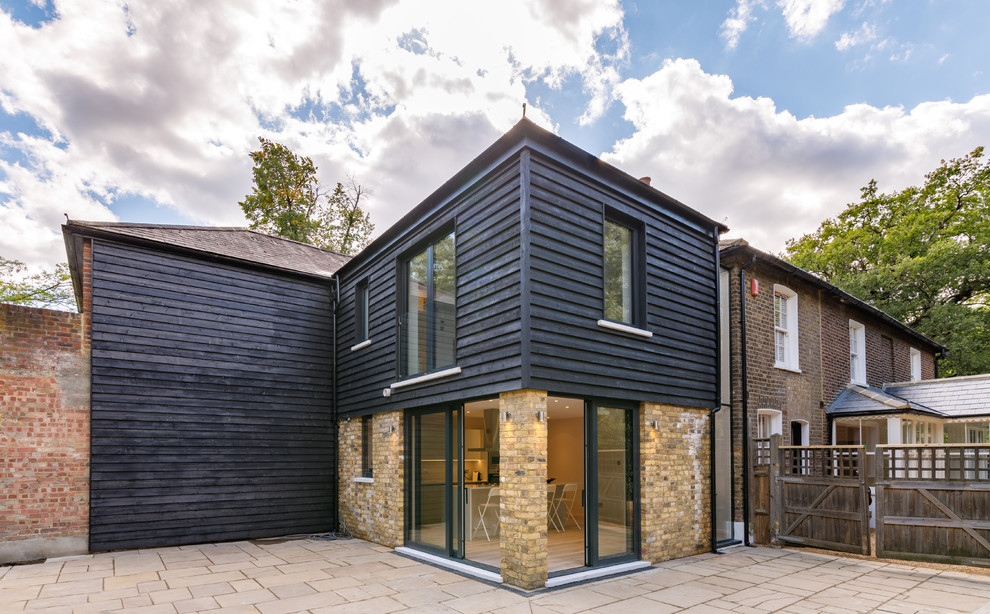 Mid-sized trendy black two-story wood duplex exterior photo in London with a hip roof and a tile roof