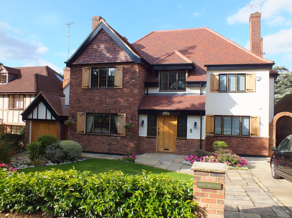 Design ideas for a large and red traditional brick house exterior in London with three floors and a pitched roof.