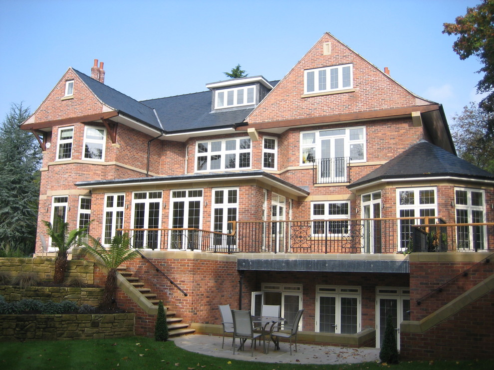 Immagine della facciata di una casa rossa classica a due piani con rivestimento in mattoni