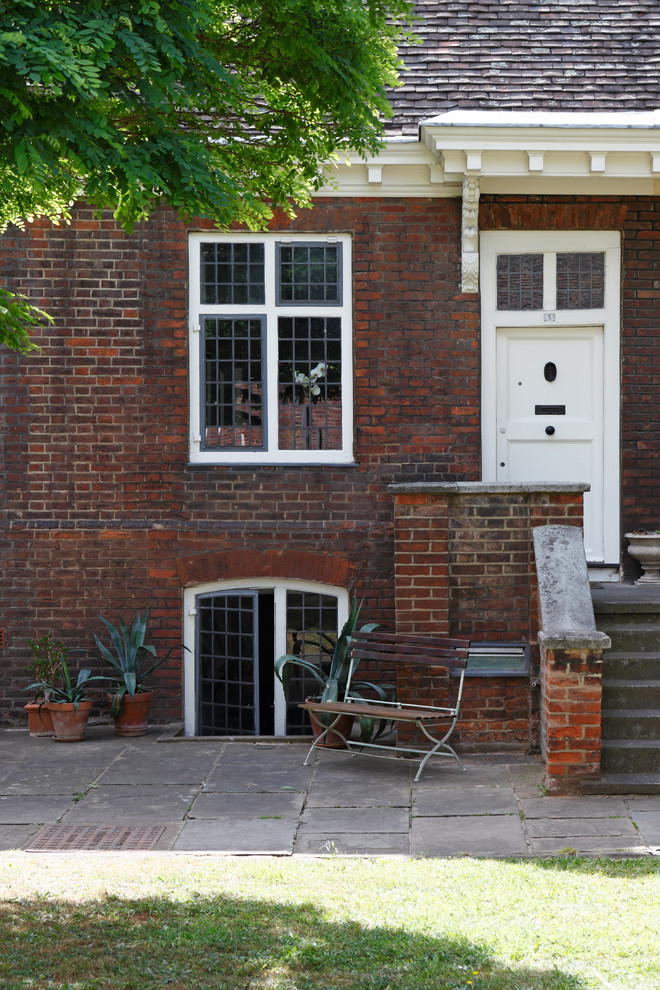 This is an example of a small and red traditional two floor brick house exterior in London with a pitched roof.