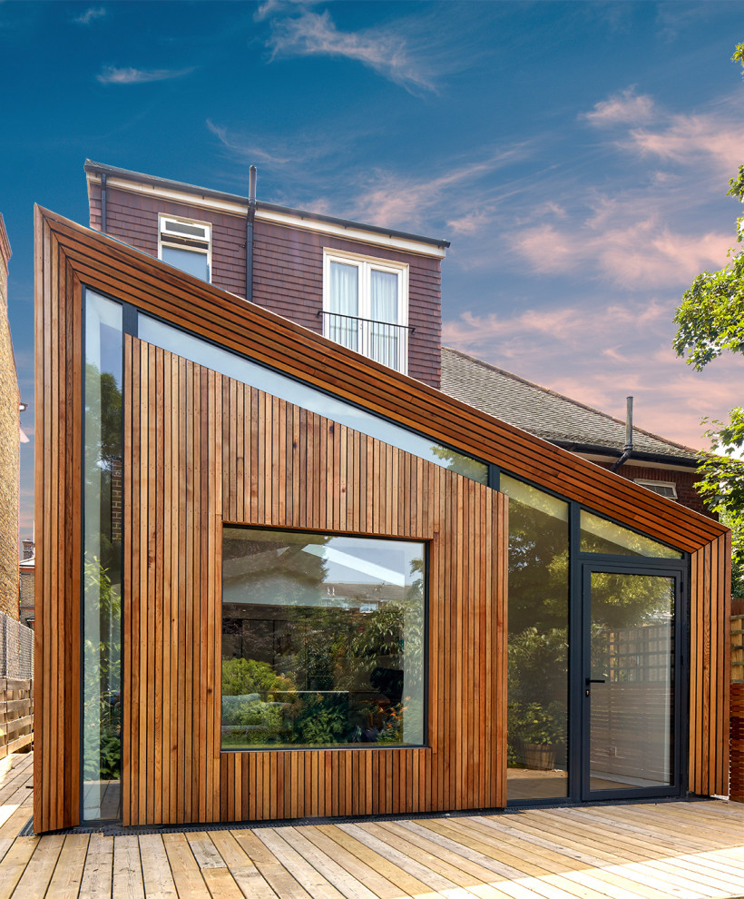 Large and brown contemporary bungalow detached house in London with wood cladding and a lean-to roof.