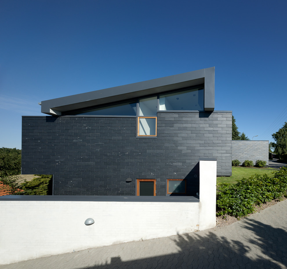 Inspiration för ett mellanstort funkis svart hus i flera nivåer, med tegel och pulpettak
