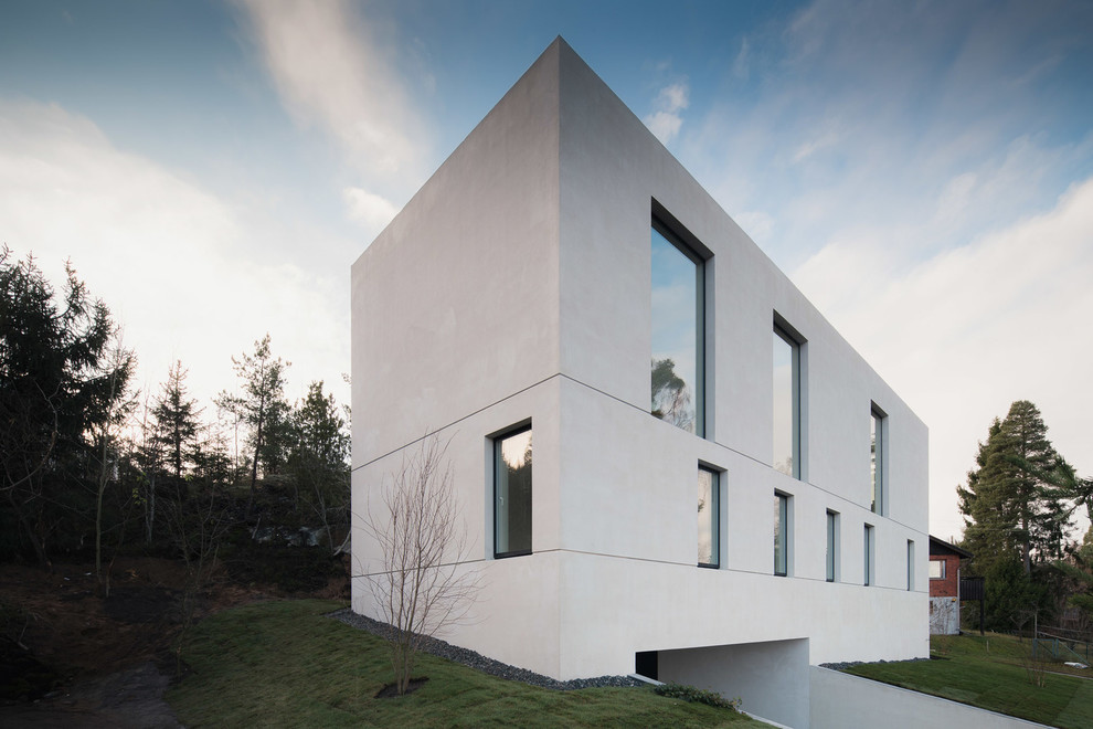 Foto på ett stort minimalistiskt vitt stenhus, med tre eller fler plan och platt tak