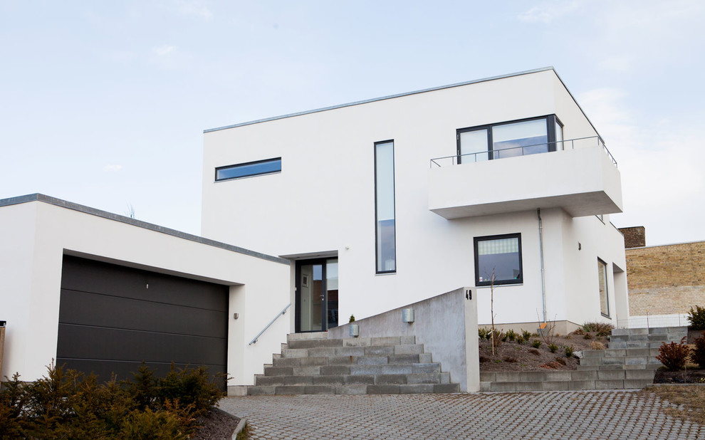 Aménagement d'une grande façade de maison blanche moderne en panneau de béton fibré à un étage avec un toit plat.