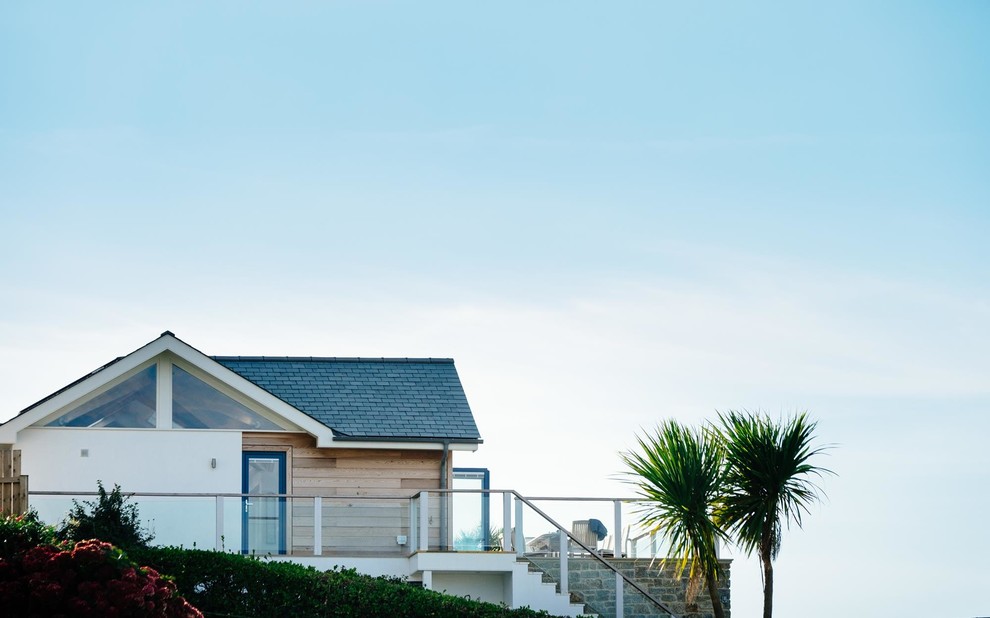 Design ideas for a white beach style bungalow house exterior in Cornwall with wood cladding and a pitched roof.