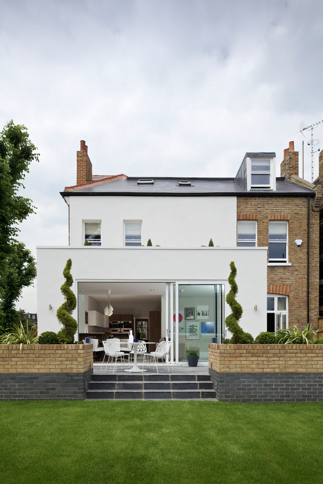 Cette photo montre une façade de maison blanche tendance à niveaux décalés avec un revêtement mixte et un toit à deux pans.