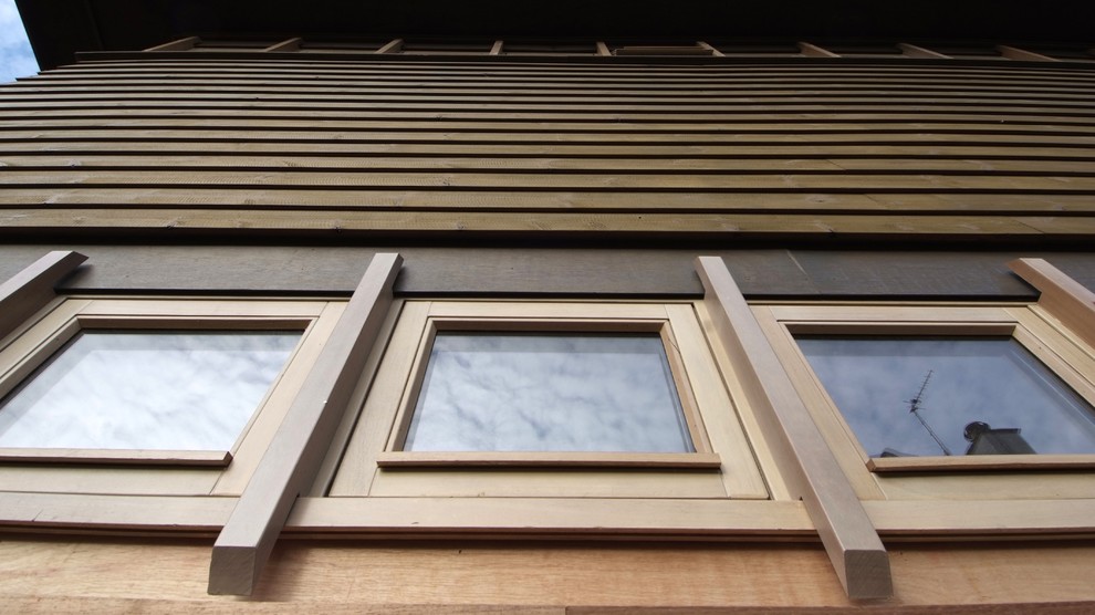 Idée de décoration pour une grande façade de maison design en bois à deux étages et plus.