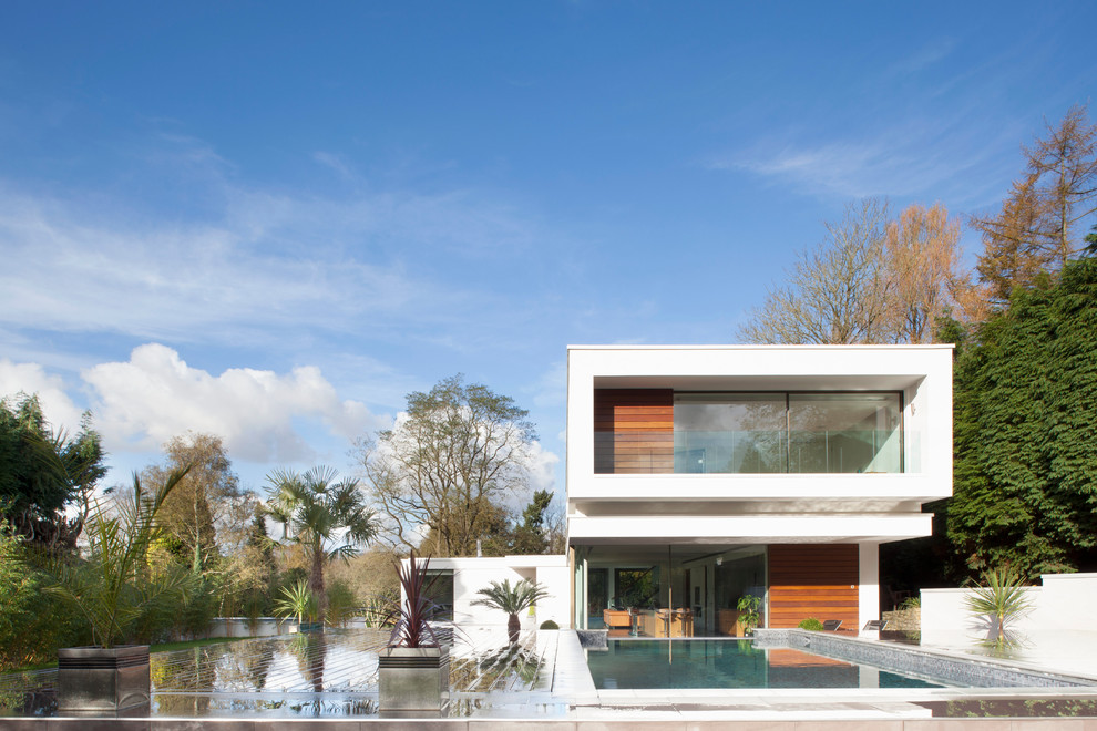 Cette image montre une façade de maison blanche minimaliste à un étage avec un revêtement mixte et un toit plat.
