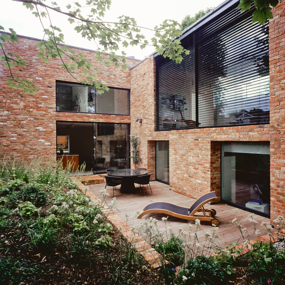 Inspiration för mellanstora moderna röda hus, med tre eller fler plan, tegel, platt tak och tak i mixade material