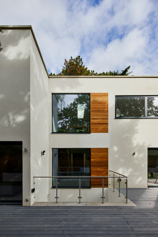 Inspiration for a white modern render detached house in London with three floors and a flat roof.