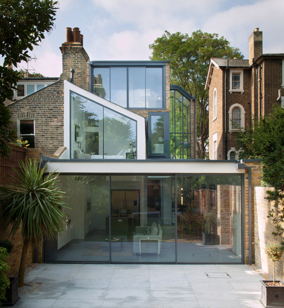 ロンドンにある高級なモダンスタイルのおしゃれな家の外観 (ガラスサイディング、デュープレックス) の写真
