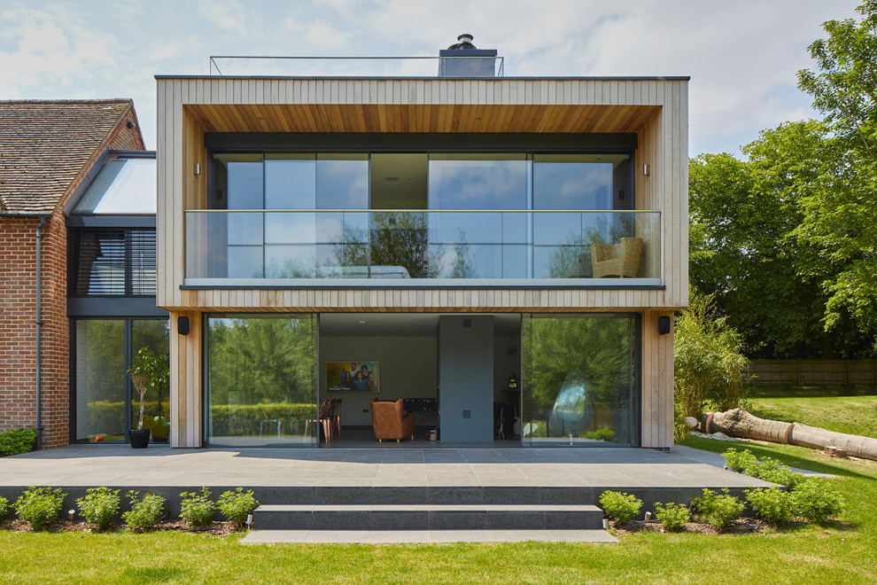 Imagen de fachada de casa actual de dos plantas con revestimiento de madera y tejado plano