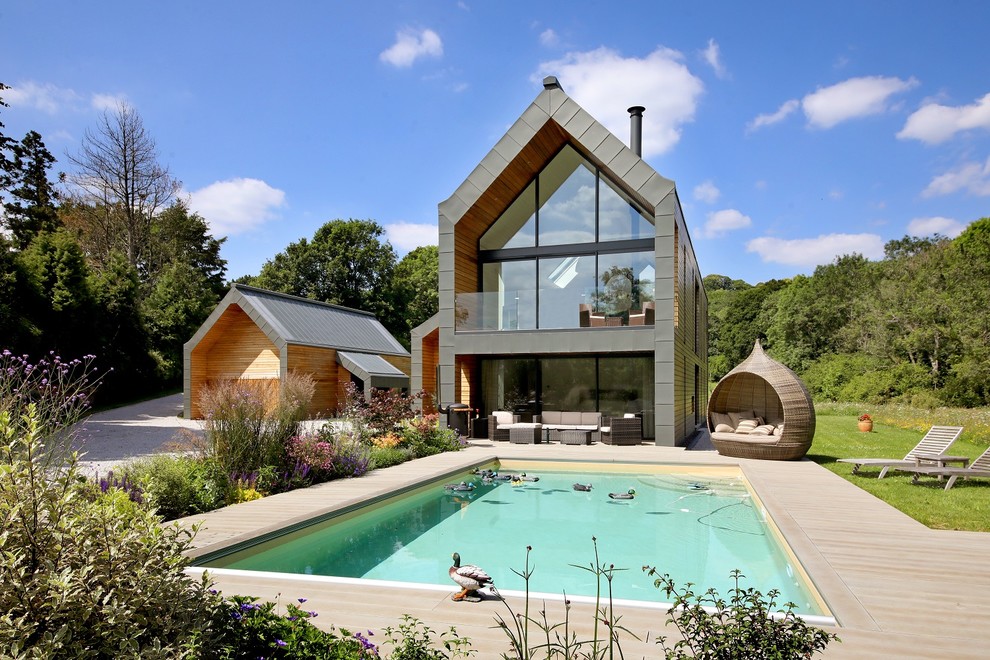 This is an example of a gey rural two floor glass detached house in Surrey with a pitched roof.