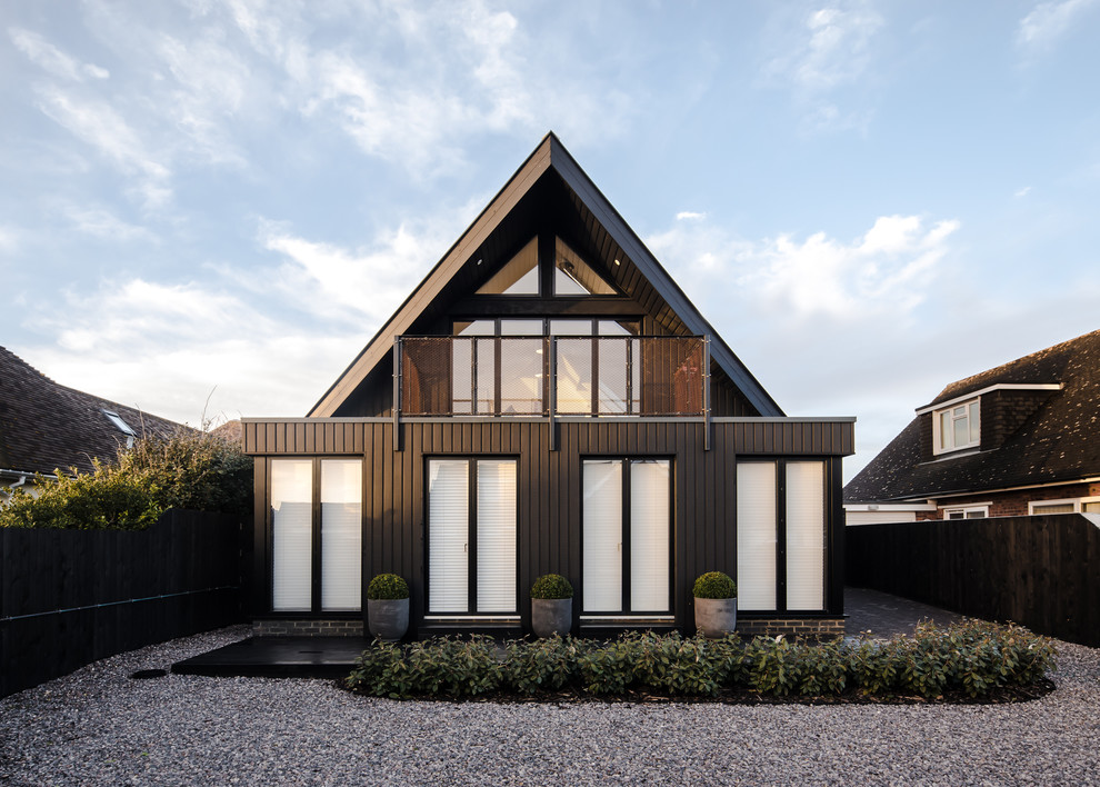 Cette image montre une façade de maison noire design à un étage avec un toit à deux pans.