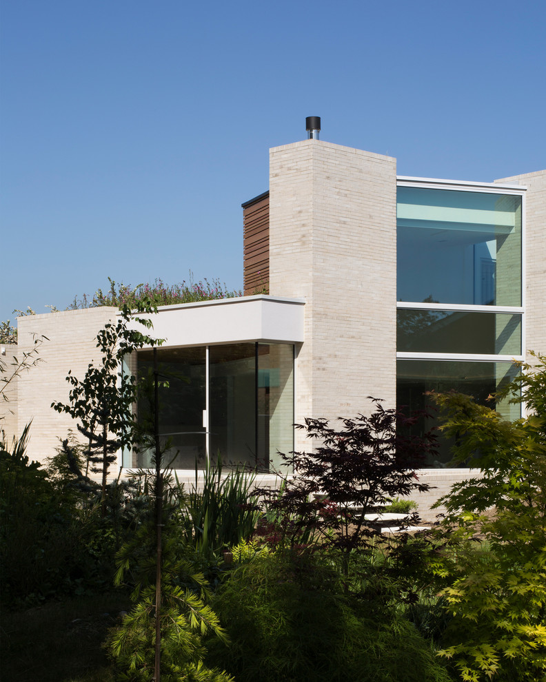 Inspiration for a mid-sized contemporary white two-story brick exterior home remodel in Cambridgeshire with a green roof