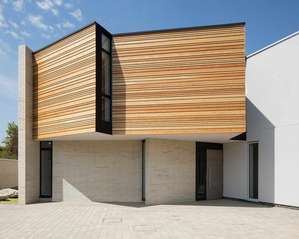 Aménagement d'une façade de maison beige contemporaine en bois à un étage avec un toit plat et un toit mixte.