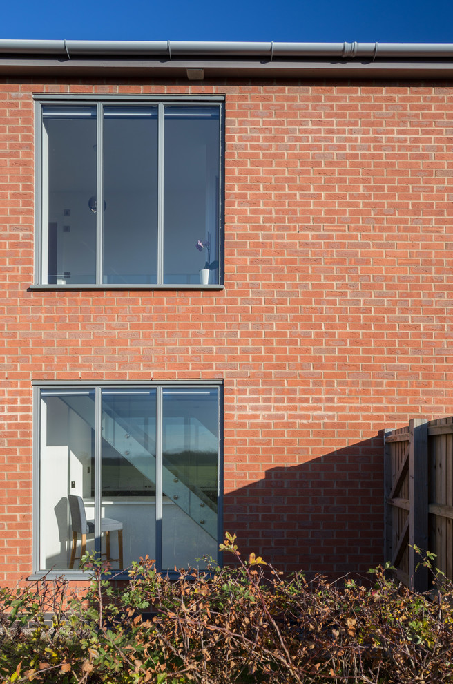 Diseño de fachada de casa bifamiliar multicolor contemporánea pequeña de dos plantas con revestimiento de ladrillo, tejado a dos aguas y tejado de teja de barro
