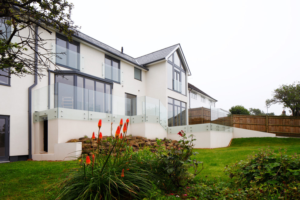 Large and white contemporary render house exterior in Sussex with three floors and a pitched roof.