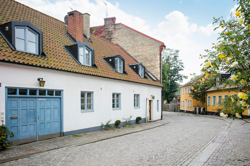 Cette photo montre une façade de maison blanche scandinave en pierre de taille moyenne et de plain-pied avec un toit à deux pans.