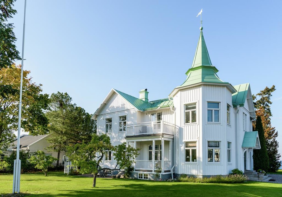 Esempio della villa grande bianca stile marinaro a due piani con rivestimento in legno e copertura in metallo o lamiera