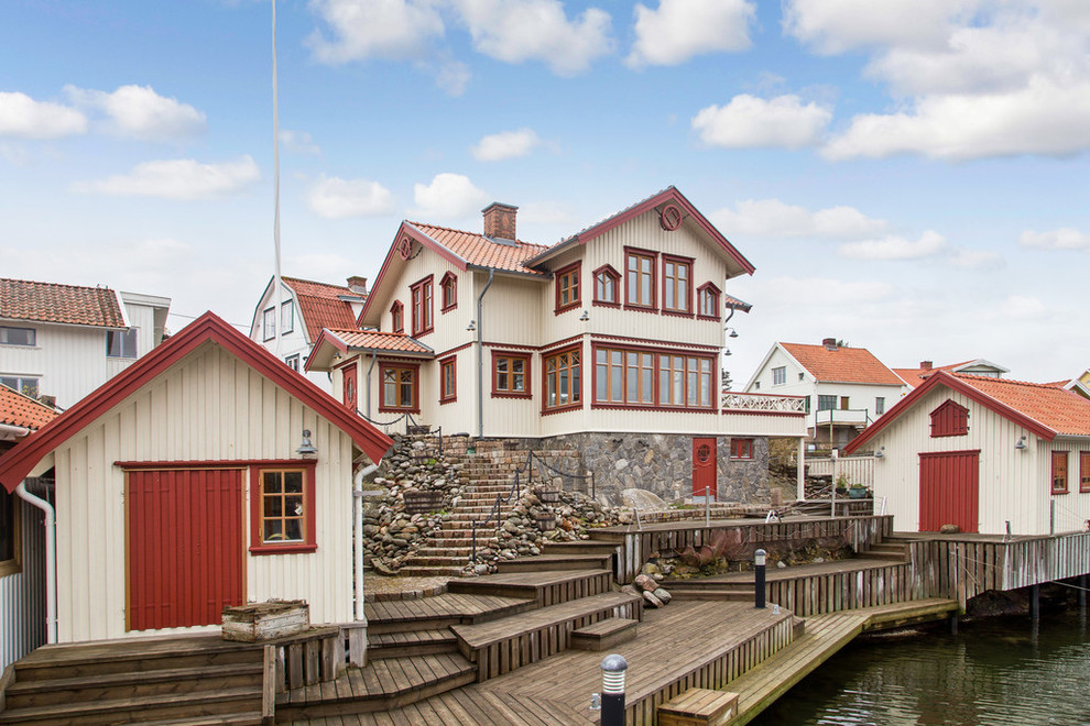 Idee per la facciata di una casa grande beige scandinava a due piani con rivestimento in legno e tetto a capanna