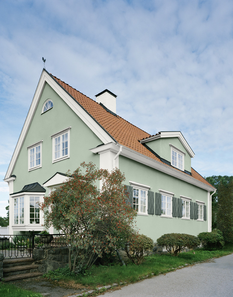 Modelo de fachada verde clásica renovada grande de dos plantas con revestimiento de adobe y tejado a dos aguas