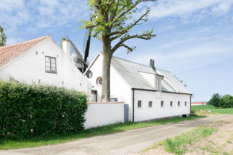 На фото: большой, двухэтажный, белый барнхаус (амбары) дом в стиле кантри с крышей из смешанных материалов с